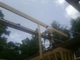 Carpenter setting a ridge beam over a new addition frame — Ice Dam Removal by Roofing Brothers in Belews Creek