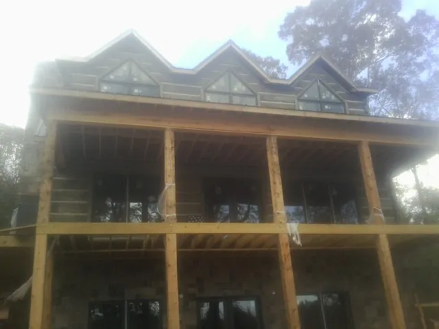 Dormers and porch framing on a large log home under construction — Roof Coating work by our crew in Belews Creek