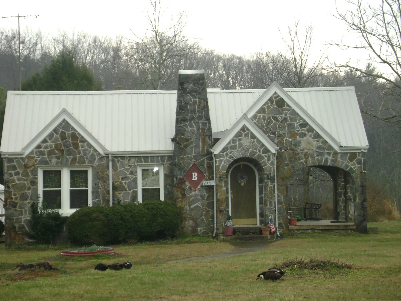 White metal roof on a stone cottage with steep gables in Belews Creek