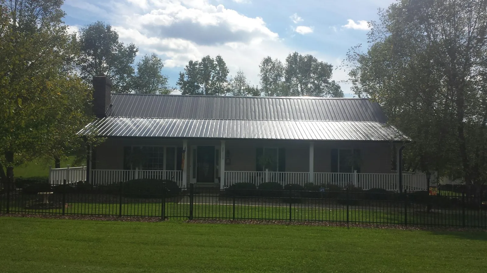 Gray metal roof on a brick ranch with a full width front porch — Gutter Guard Installation work by our crew in Belews Creek