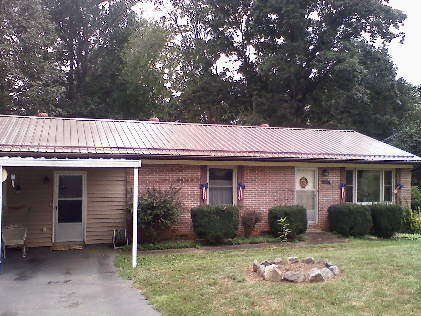 Bronze metal roof and carport on a brick ranch home — Roof Repair work by our crew in Belews Creek